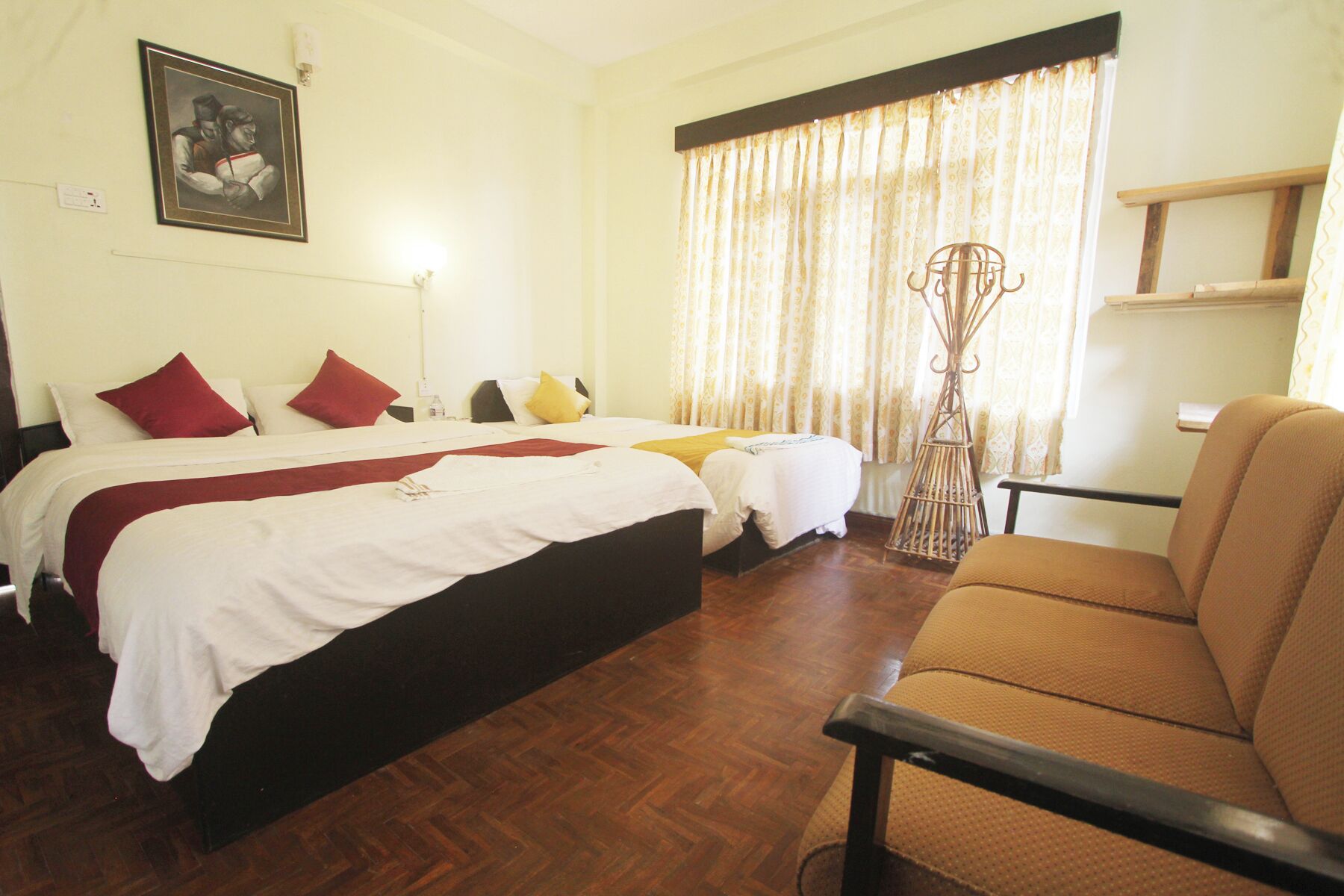 A hotel room with a large bed, two smaller beds, a chair, and a decorative metal stand.