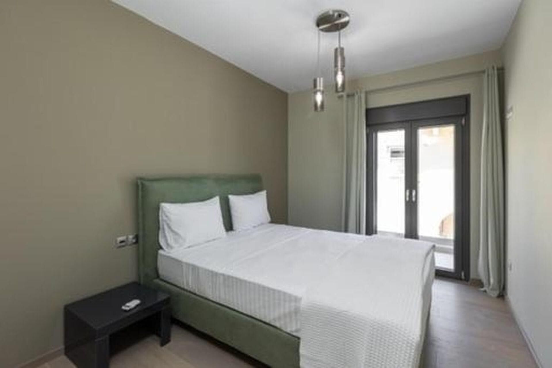 Un dormitorio con cama, mesita de noche y lámpara del techo.