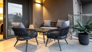 Ein Balkon mit zwei Korbstühlen, einem kleinen Tisch und einem Blumentopf.