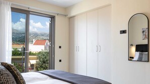 Ein Schlafzimmer mit Bett, großem Kleiderschrank, einer Glastür zum Balkon und einem Spiegel an der Wand.