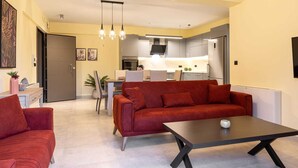 Een moderne woonkamer met een rode bank, een salontafel en een eethoek met een tafel en stoelen.