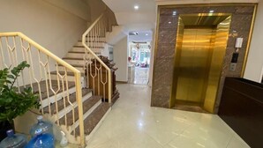 A hotel lobby with a marble floor, a staircase with a white railing, and a gold elevator. - Hanoi Milton Boutique Hotel  (Hanoi)