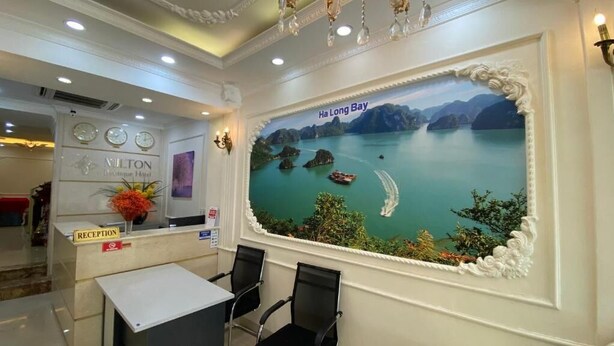 A reception area with a mural of Ha Long Bay, a reception desk, and a clock. - Hanoi Milton Boutique Hotel  (Hanoi)