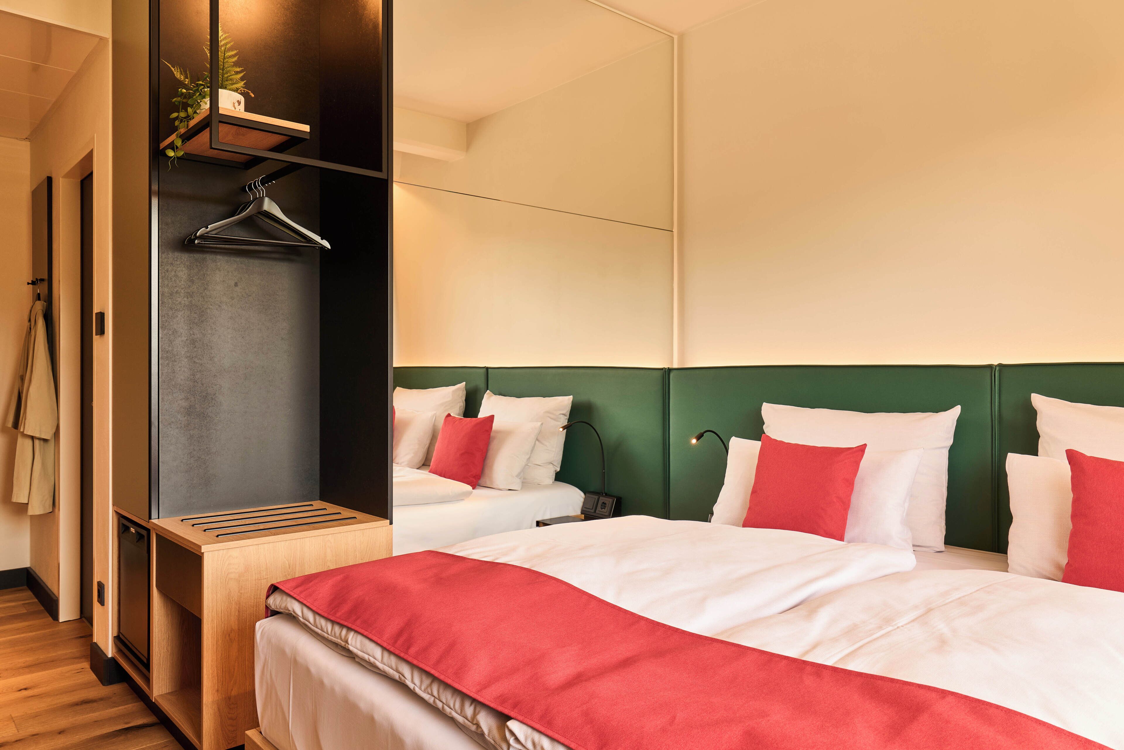 Ein Hotelzimmer mit Bett, Nachttisch, Spiegel und Kleiderhaken.