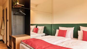 Ein Hotelzimmer mit Bett, Nachttisch, Spiegel und Kleiderhaken.