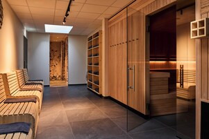Uma área de spa com bancos de madeira, sauna e um armário envidraçado.