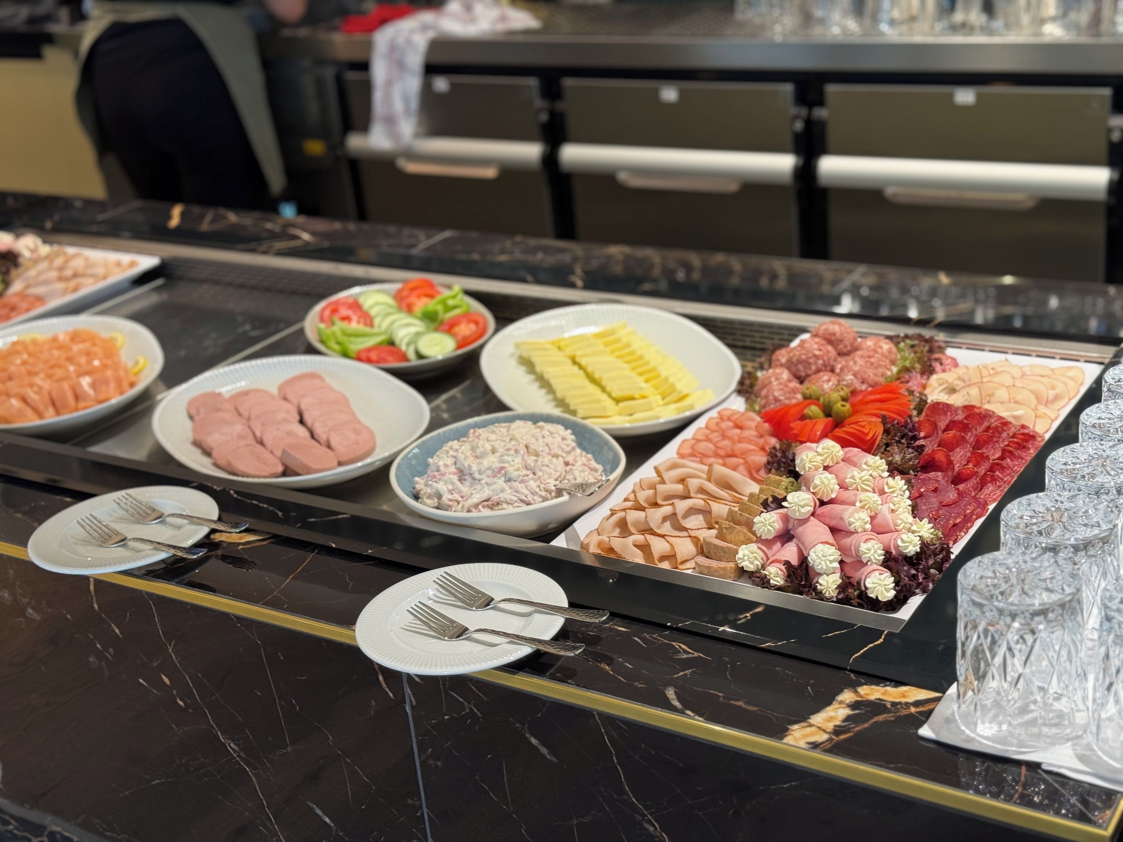 Ett buffébord med olika sorters mat och serveringsredskap.