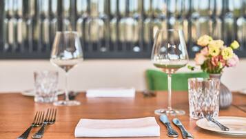 A dining table set with wine glasses, cutlery, and a vase of flowers.
