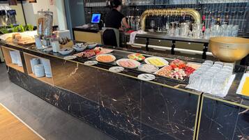 A buffet counter with various food items and a large bowl of champagne.