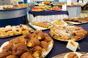 Un bufé con diversas opciones de panadería, incluyendo croissants, pasteles y gofres.