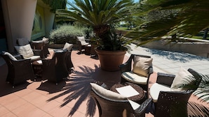An outdoor seating area with wicker chairs and a large potted plant. - Exclusive suite with sunny terrace (Bibione)
