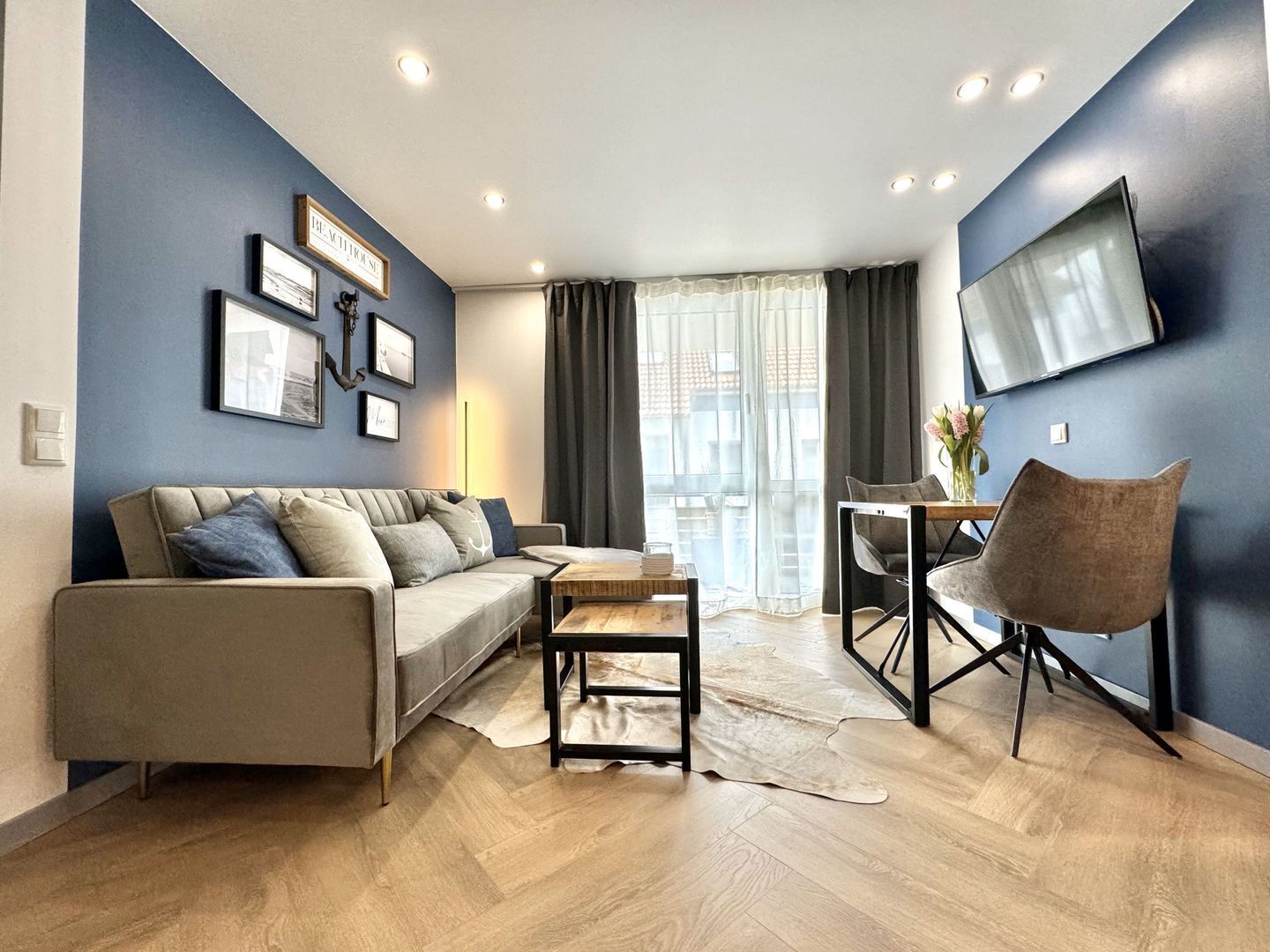Ein modernes Wohnzimmer mit einer Couch, einem Couchtisch und einem an der Wand befestigten Fernseher.