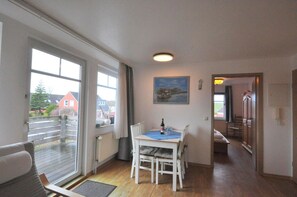A room with a dining table, chairs, a radiator, a window, a painting, and a door leading to another room.
