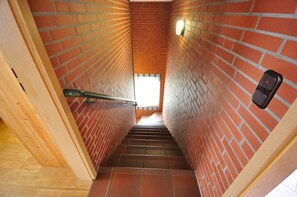 A brick stairway with a handrail, a light fixture, and a door at the top.