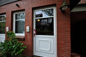 Ein rot backsteiner Gebäude mit einer weißen Tür, einem kleinen Fenster und einem roten Griff.