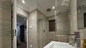 Un baño moderno con un lavamanos grande, cabina de ducha de vidrio y un espejo.
