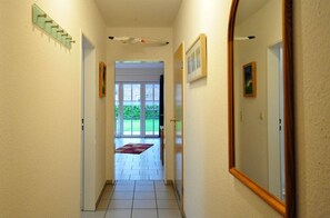 Ein Flur mit einer Glastür, die auf einen Balkon mit einer roten Teppich führt.