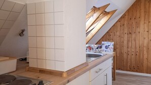 A modern kitchen with white cabinetry, a wooden countertop, and a built-in stove. - Vacation apartment Orchidee - Haus am Brunnen (Werdum)