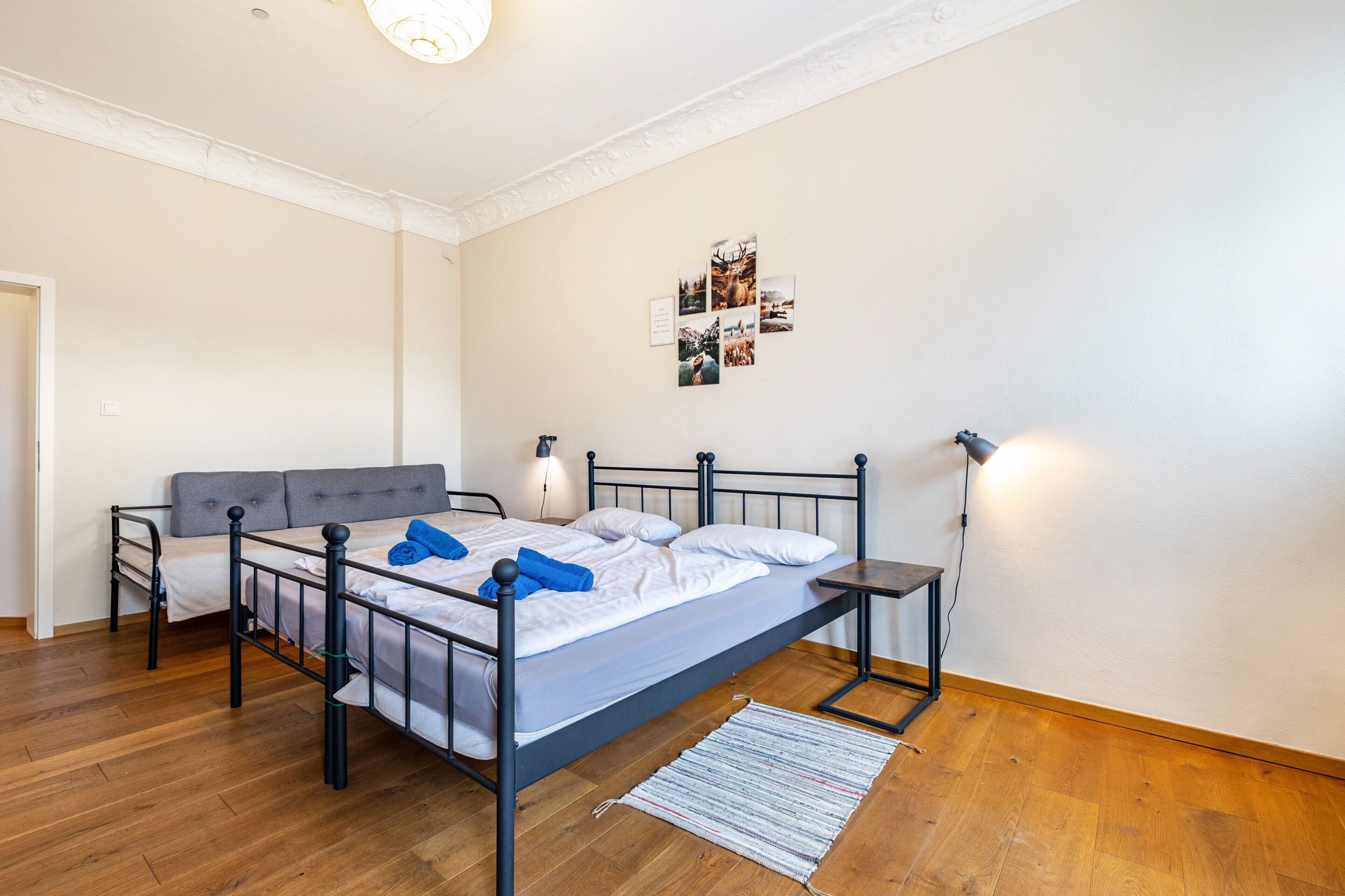 A bedroom with a bed, bedside tables, a lamp, a rug, and wall decorations.