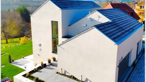 Een modern, twee verdiepingen hoog gebouw met een plat dak, een groot raam op de begane grond en een klein balkon.