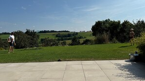 Een terras met uitzicht op een groen veld en bomen.