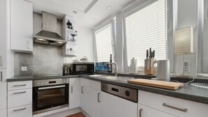 Eine moderne Küche mit weißen Schränken, einem eingebauten Backofen, einer Mikrowelle und einem Geschirrspüler.