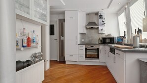 Eine moderne Küche mit weißen Schränken, einem eingebauten Backofen, einer Mikrowelle und einer Edelstahl-Dunstabzugshaube.