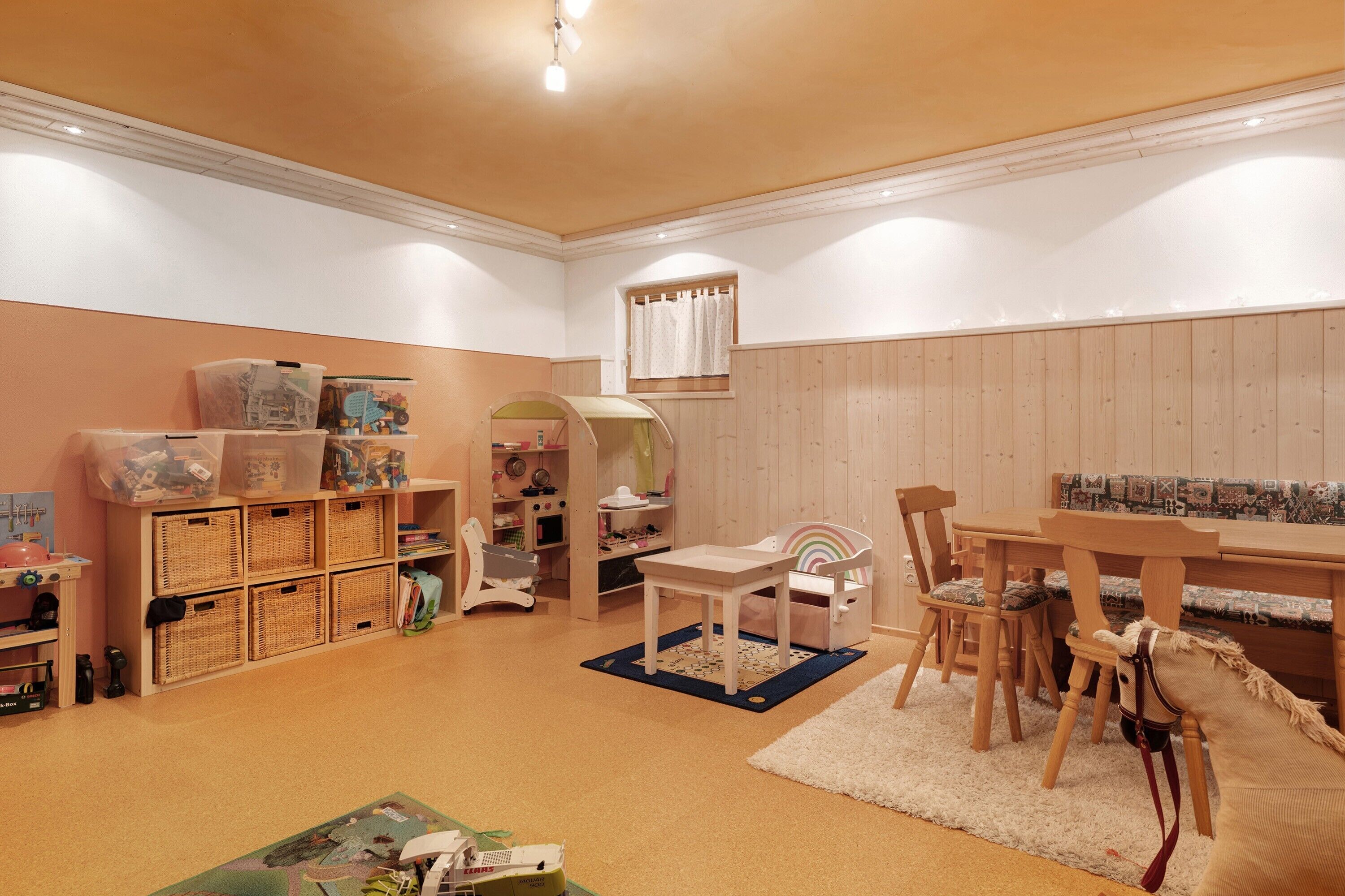 Ein Kinderzimmer mit Holztisch, Stühlen und einem Bücherregal.