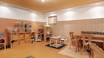 Ein Kinderzimmer mit Holztisch, Stühlen und einem Bücherregal.