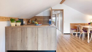 Une cuisine dotée de meubles de rangement en bois, d’un plan de travail en bois et d’un coin repas avec une table et des chaises en bois.