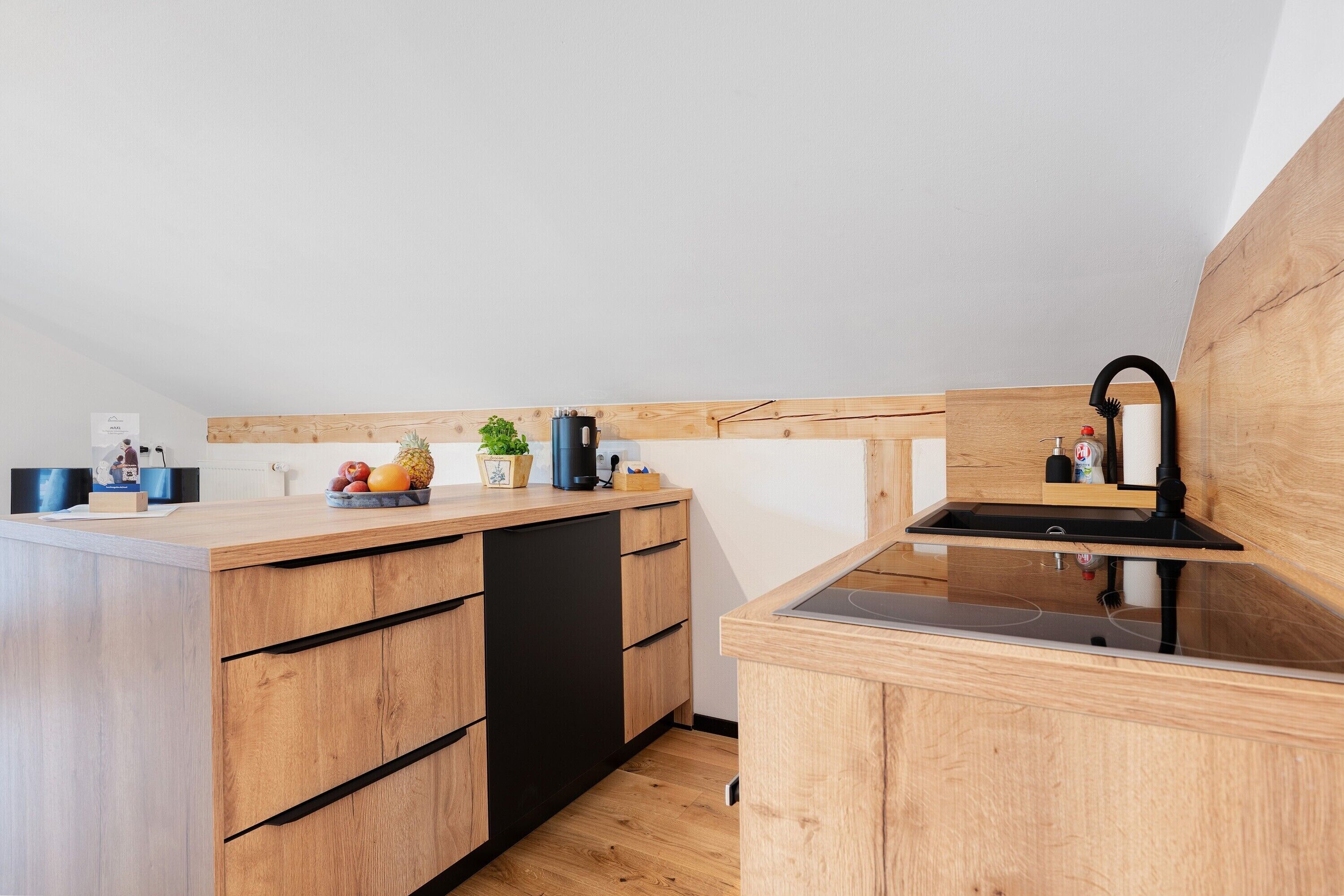 Una cocina compacta con armarios de madera, lavavajillas negro y estufa integrada.