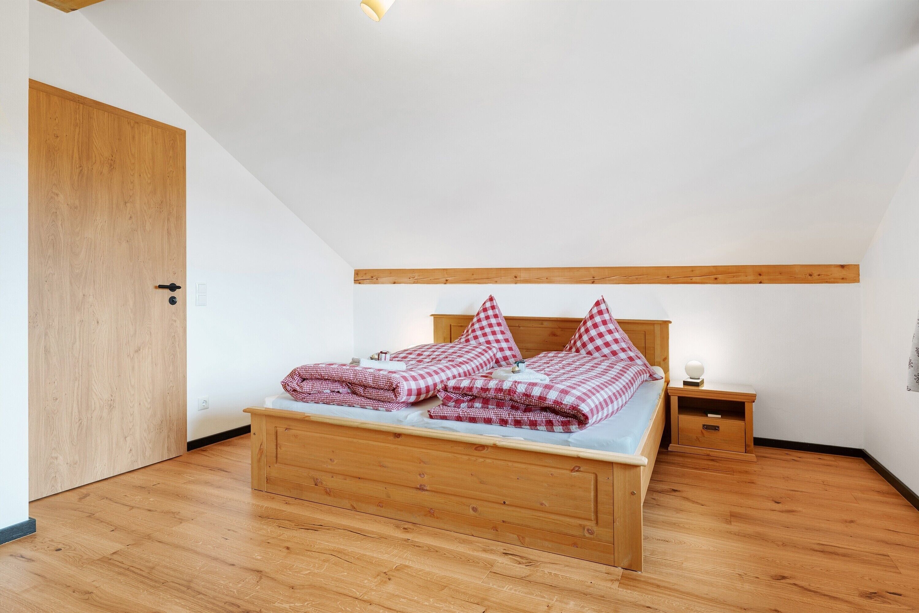 Ein Schlafzimmer mit einem hölzernen Bett, einem Nachttisch und einer Holztür.