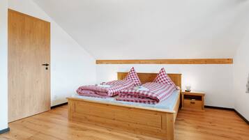 Ein Schlafzimmer mit einem hölzernen Bett, einem Nachttisch und einer Holztür.