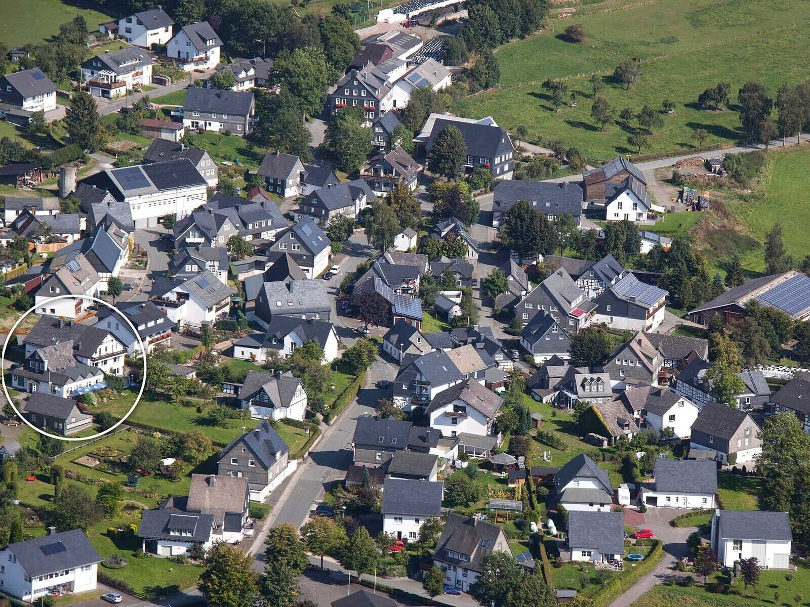 An aerial view of a residential area with houses, roads, and green spaces.