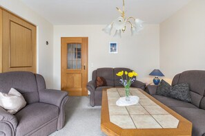 A living room with two sofas, a coffee table, a chandelier, and a door with frosted glass panels. - Apartment 'Ilse' with Private Terrace, Shared Garden and Wi-Fi (Schülperweide)