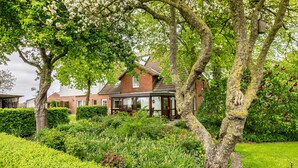 A house with a garden, a conservatory, and a brick facade. - Apartment 'Ilse' with Private Terrace, Shared Garden and Wi-Fi (Schülperweide)