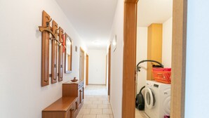 A hallway with a wooden bench, a washing machine, and a laundry basket. - Apartment 'Ilse' with Private Terrace, Shared Garden and Wi-Fi (Schülperweide)