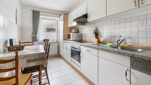 A kitchen with white cabinets, a microwave, an oven, and a sink. - Apartment 'Ilse' with Private Terrace, Shared Garden and Wi-Fi (Schülperweide)