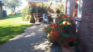 A paved pathway leading to a patio area with a table and chairs, surrounded by potted plants and a brick wall. - Apartment 'Ilse' with Private Terrace, Shared Garden and Wi-Fi (Schülperweide)