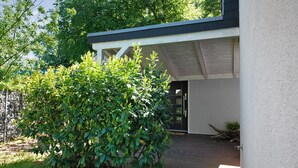 Ein modernes Gebäude mit Holzterrasse, kleinem Garten und einer Tür zum Innenraum.