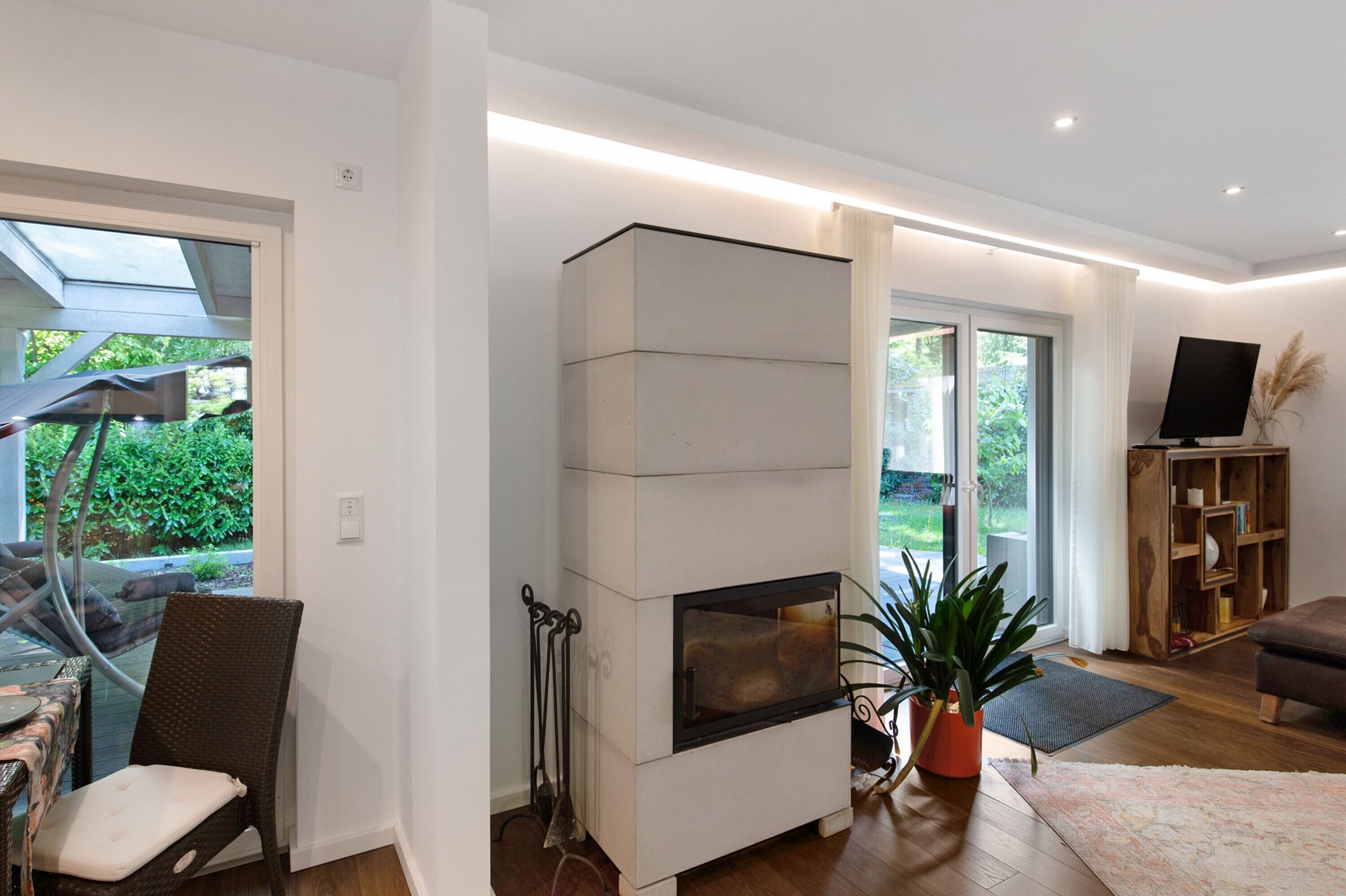 A modern living room with a fireplace, a dining area with outdoor view, and a TV stand.