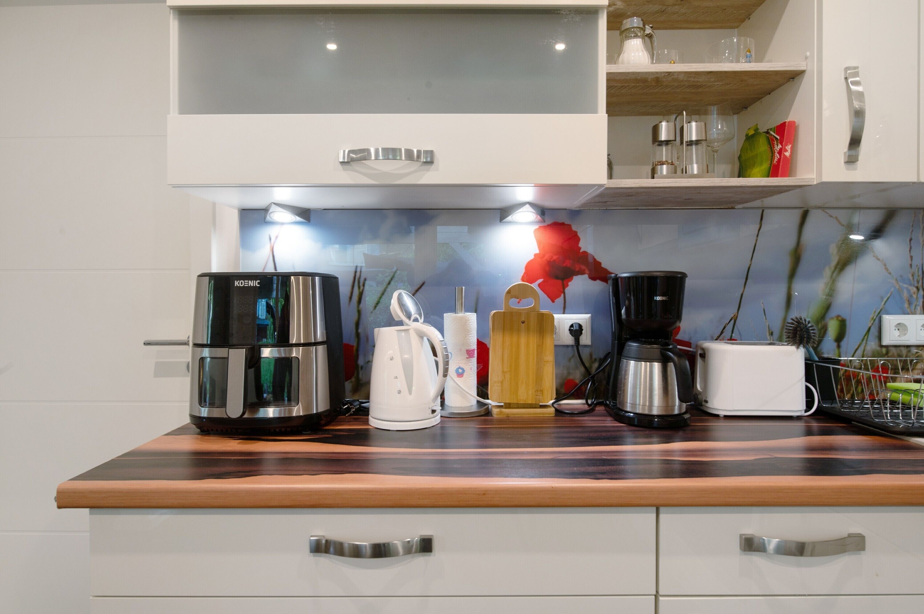 Eine Küche mit Kaffeemaschine, Wasserkocher, Toaster und einem Holzschneidebrett.