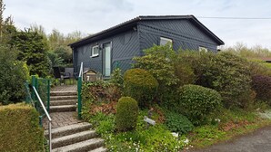 Uma casa com escadaria que leva à porta da frente, rodeada por vegetação exuberante e um jardim bem cuidado.