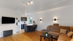 Uma sala de estar moderna com sofá, mesa de centro e TV fixada na parede.