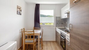 A compact kitchen with a dining table and chairs, a window with a view, and modern appliances.