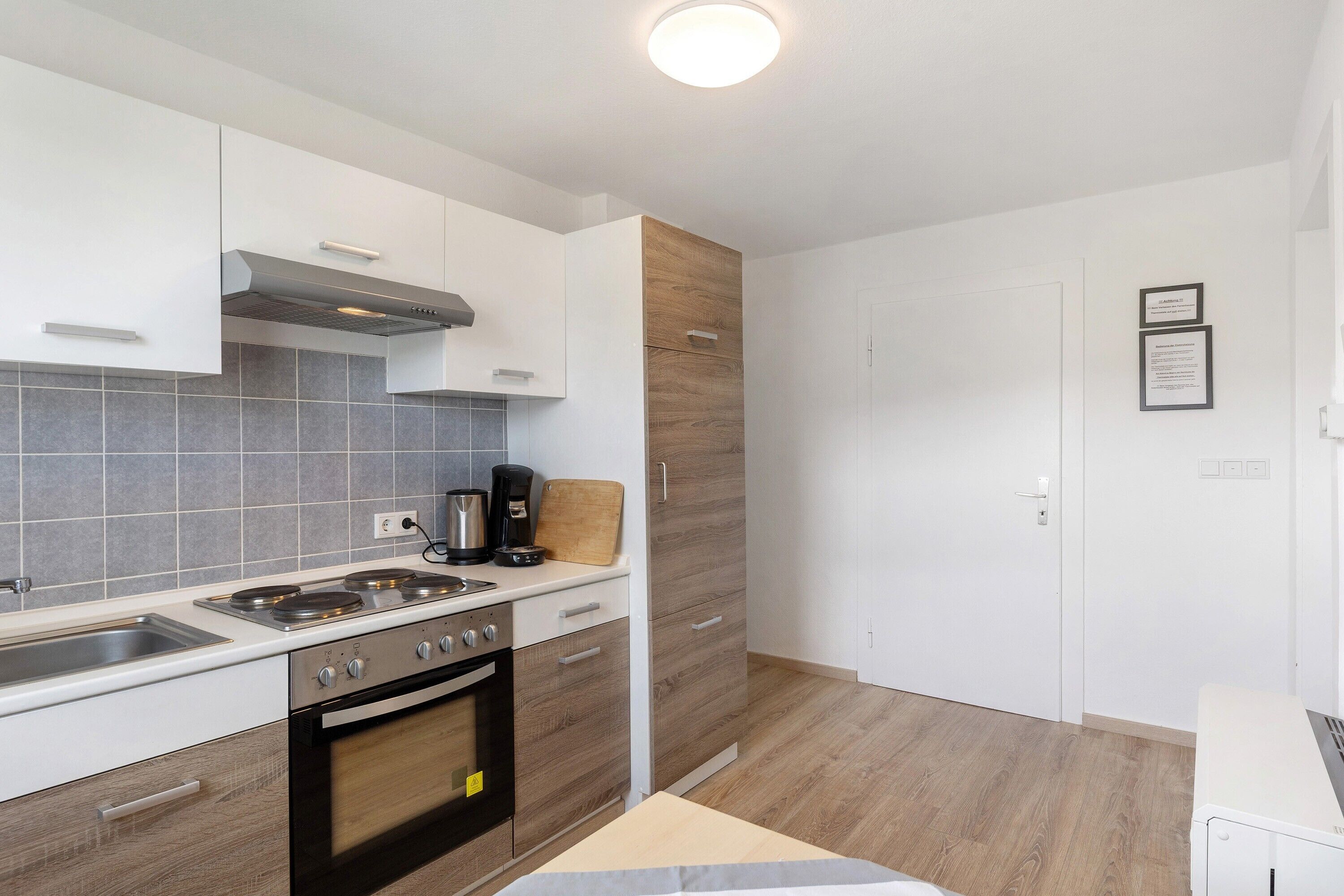 Een moderne keuken met witte kasten, een fornuis en een koffiezetapparaat.