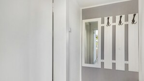 A bathroom with a white door, a mirror, and a wooden basket.