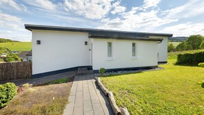 A modern single-story building with a flat roof, a small front porch, and a well-maintained lawn.