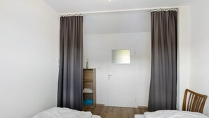 A room with two beds, a wooden wardrobe, and a door with a window.