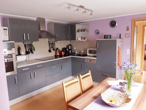A modern kitchen with grey cabinets, a wooden dining table, and a microwave.